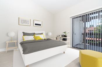 A bedroom with a white bed and a yellow chair and a balcony